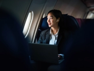 Successful Asian business woman working in airplane cabin during flight