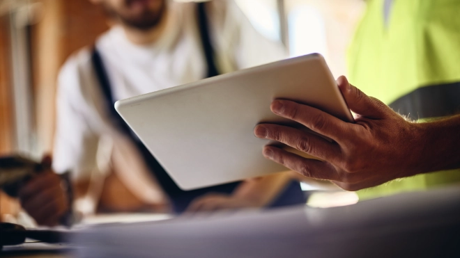 Two workers holding a tablet in a meeting on site