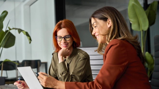 Two smiling young women reviewing work on a laptop