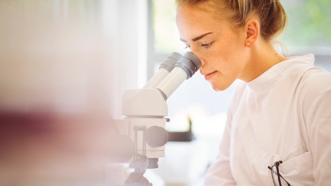 Young female pharmaceutical worker with microscope
