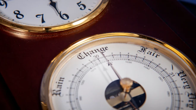 Close-up: Vintage wood/brass weather station shows a barometer face with 'Change, Rain, Fair' below a clock...