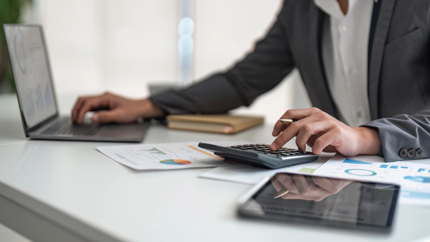 person using a calculator and laptop image